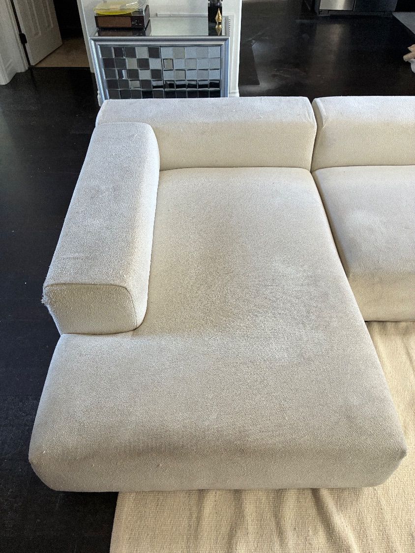Deep soil buildup visible on a white sectional chaise before cleaning