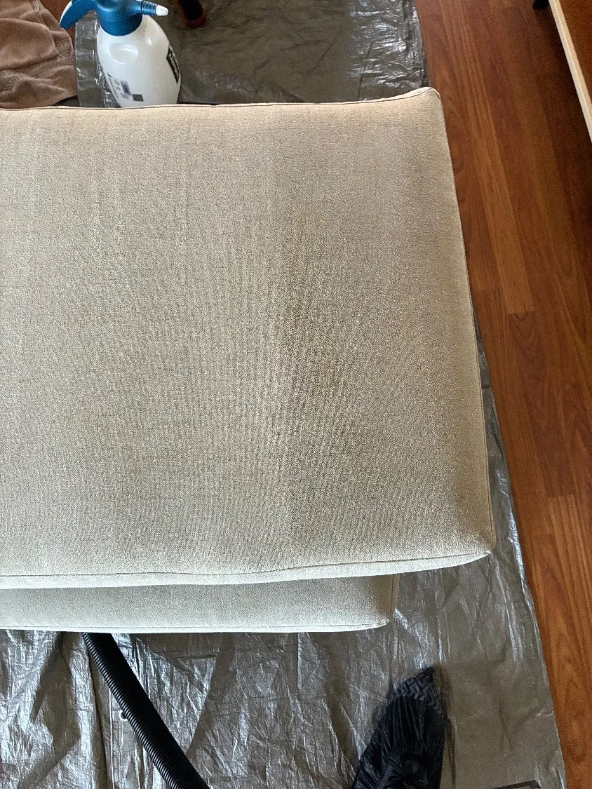 A close-up of the accent chair cushion showing greasy buildup and general soiling before cleaning