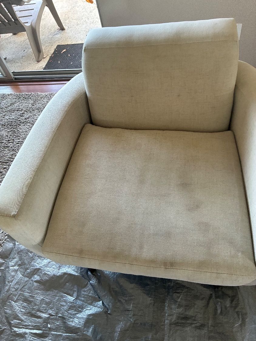 A light-colored fabric swivel accent chair in San Marcos with visible soiling and stains before cleaning