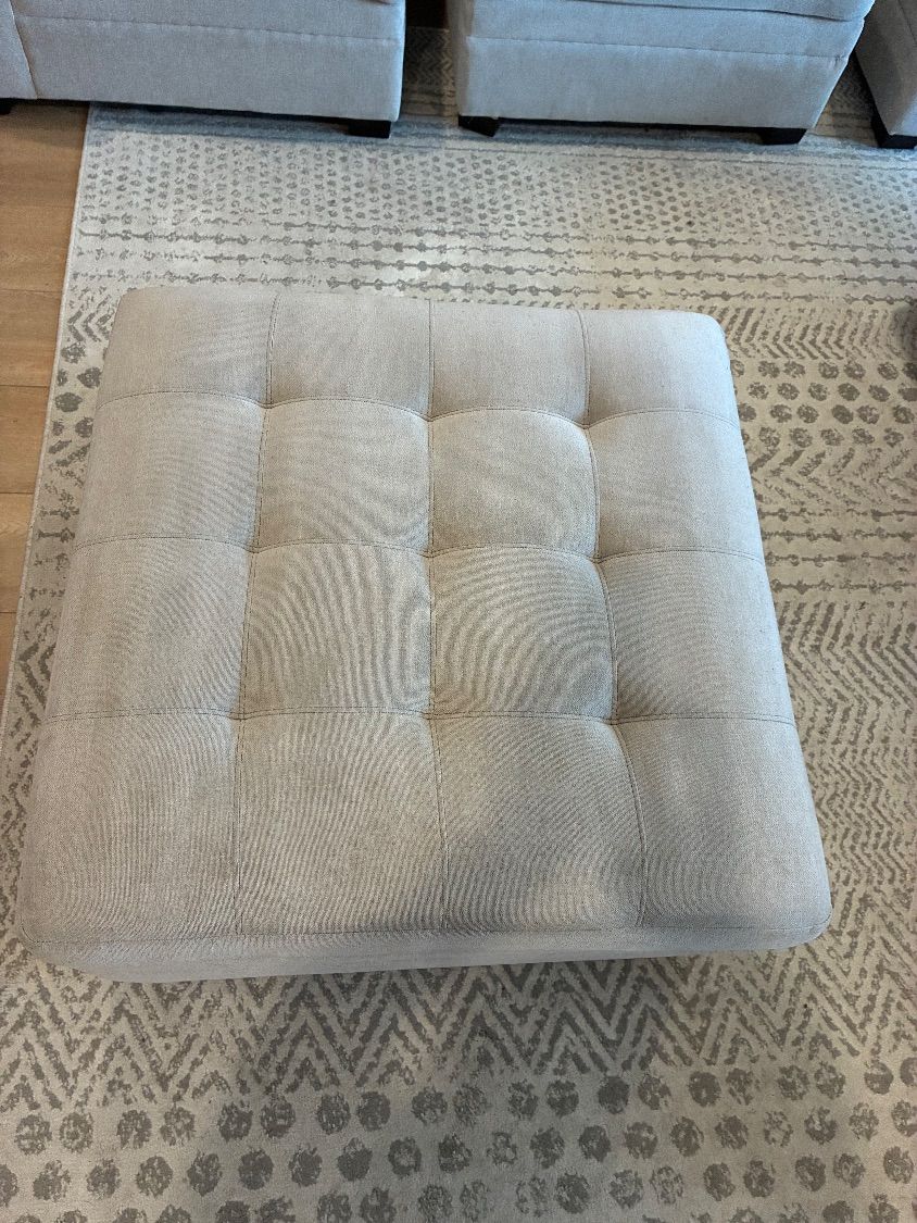 The matching light-colored ottoman after upholstery cleaning, with the sectional behind it
