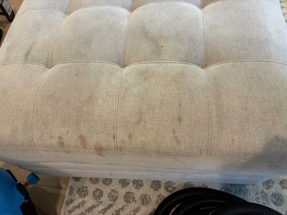 Food and drink spots on a light-colored sectional ottoman before cleaning